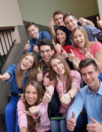 Large group of enthusiastic young professionals giving thumbs up together, symbolizing team unity, morale, and the results of effective team building coaching
